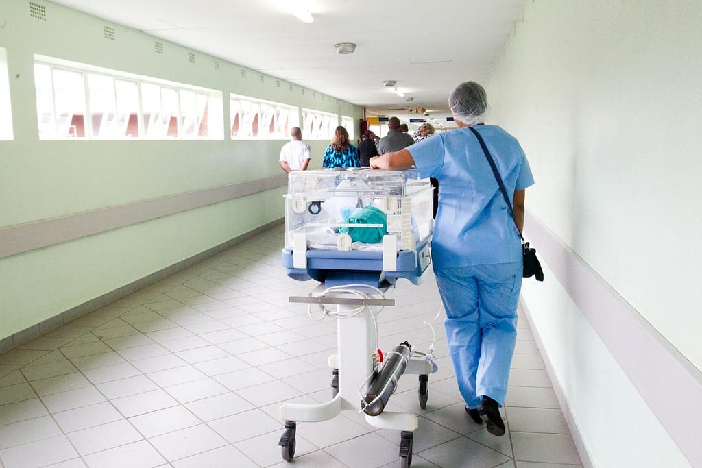 Corsia ospedaliera con operatore sanitario al lavoro - UmbertidEEventi.it Operatore sanitario in una corsia di ospedale durante attività assistenziale